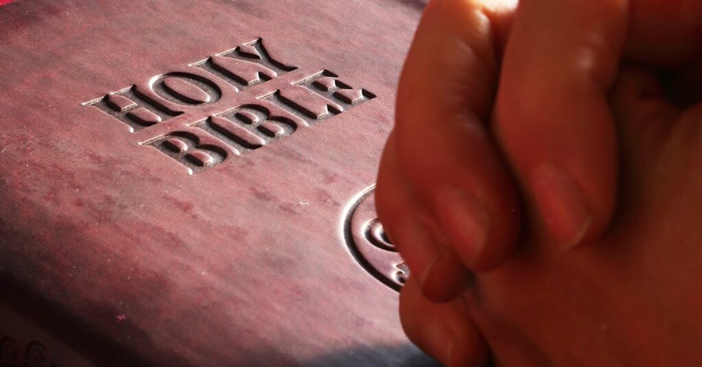Close-up of hands praying on a Holy Bible, symbolizing faith and spirituality.